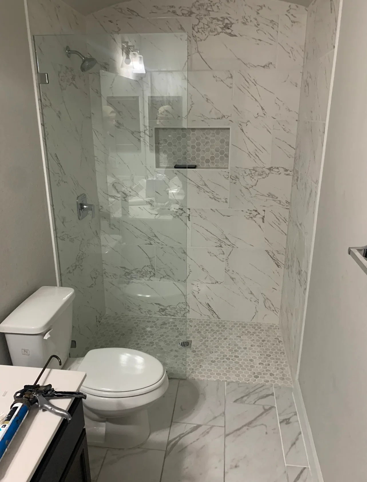 Modern bathroom with marble tile shower enclosure and hexagonal floor tiles