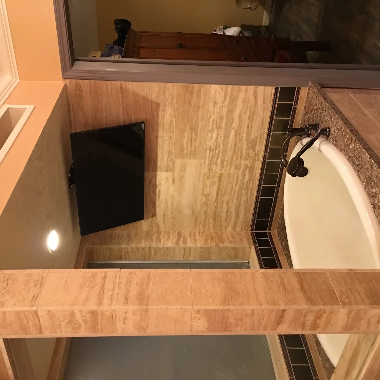 Newly remodeled bathroom with travertine tile flooring, white soaking tub, and updated fixtures