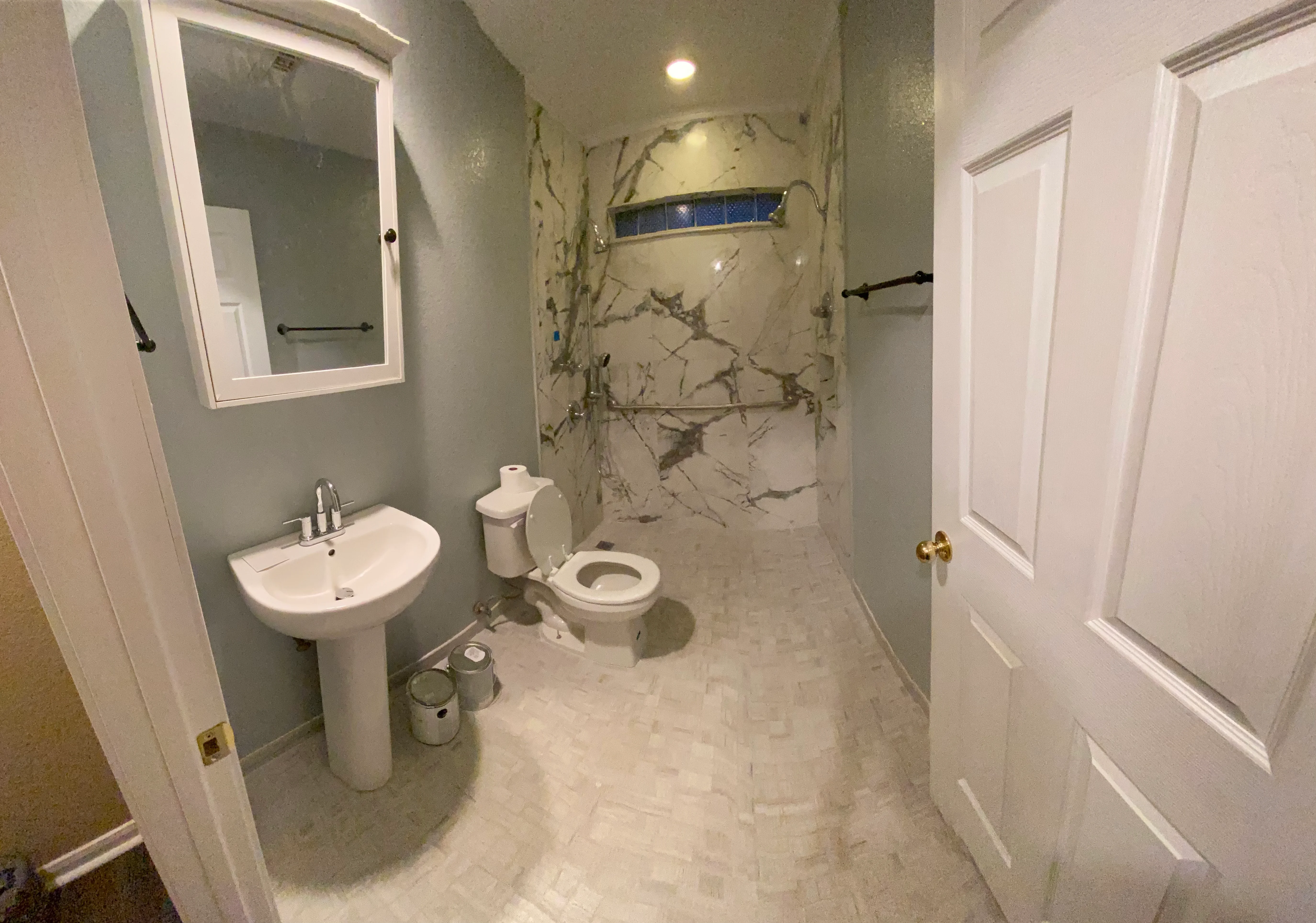 Modern bathroom with marble shower, pedestal sink, and white trim